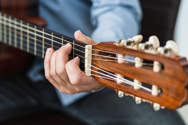 Uomo che suona una nota alla chitarra, esercitandosi con una lezione del corso online