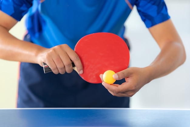 Foto maschio che gioca ping-pong con la racchetta e la palla in una palestra