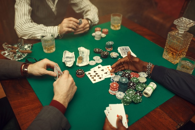 Male poker players at gaming table with green cloth