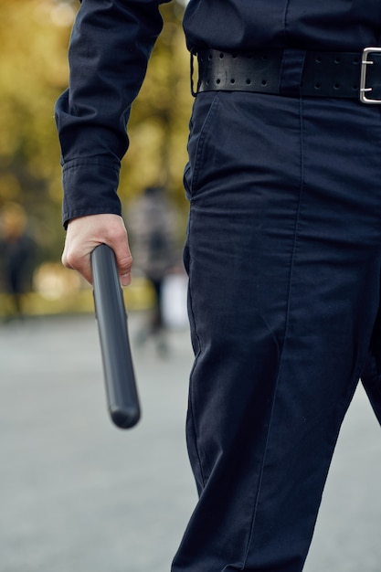 Male police officer in uniform holds baton