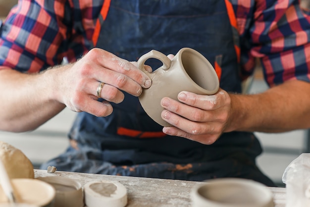 男性の陶工の手は陶器でセラミックキャップを作ります。