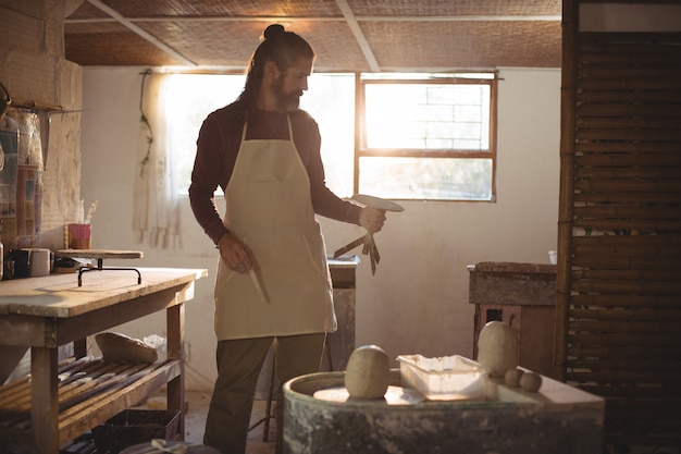 Male potter holding pottery wheel