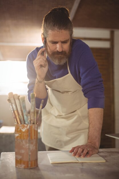 Male potter taking an order on mobile phone