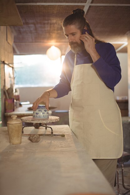 Male potter talking on mobile phone