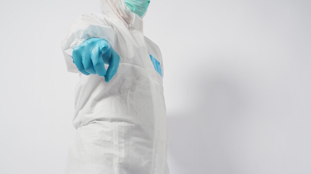 Male in PPE suite and face mask doing point hand sign on white background.