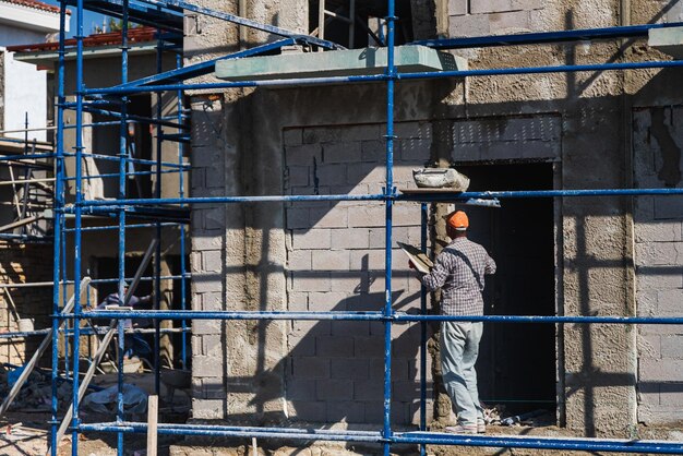 Foto muratore professionista maschio che stende il muro con pietra nuova usando una spatola