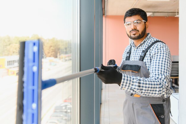 Male professional cleaning service worker cleans the windows and shop windows of a store with special equipment