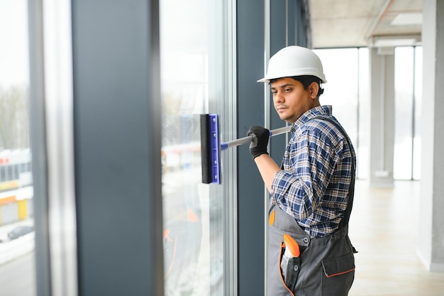 Photo male professional cleaning service worker in overalls cleans the windows and shop windows