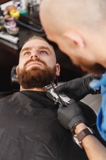 Male professional hairdresser serving client by clipper