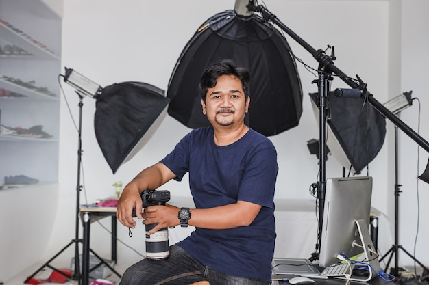 Male professional  photographer holding his camera with a set of lights in the background