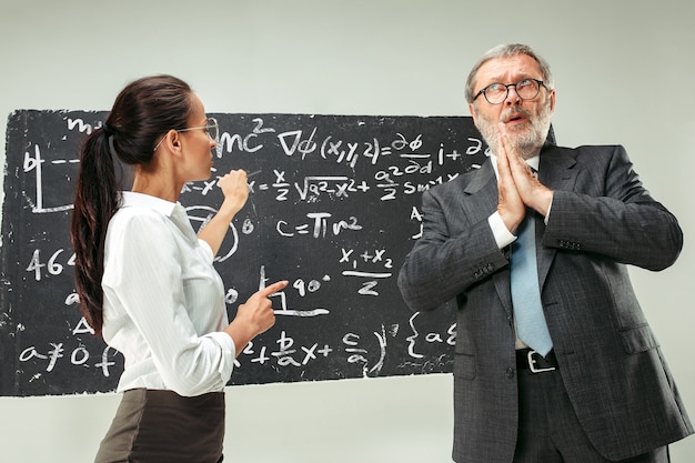 Male professor and young woman against chalkboard in classroom