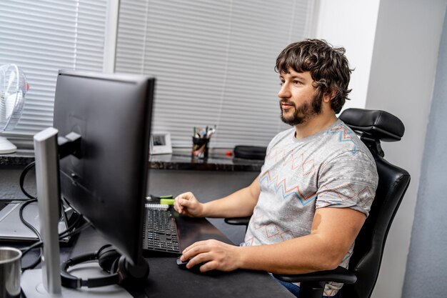 Male programmer working on desktop computer near monitor at office in software development company Website design programming and coding technologies