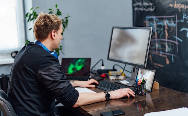 male programmer working on desktop computer near monitor at office in software development company. website design programming and coding technologies.