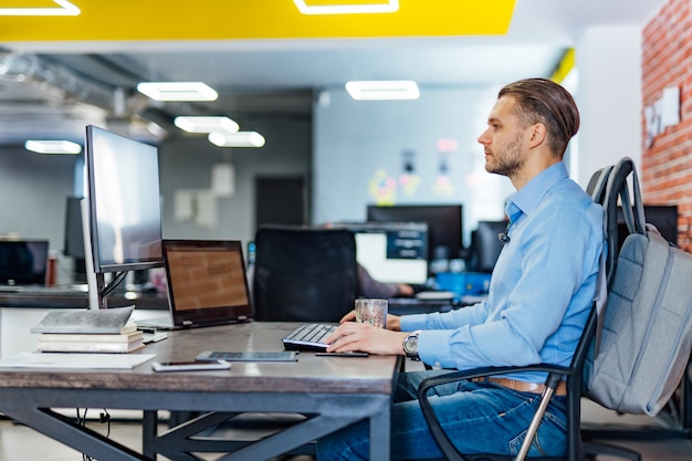 male programmer working on desktop computer with many monitors at office in software develop company. website design programming and coding technologies.