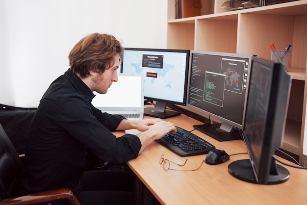 Male programmer working on desktop computer with many monitors at office in software develop company. Website design programming and coding technologies