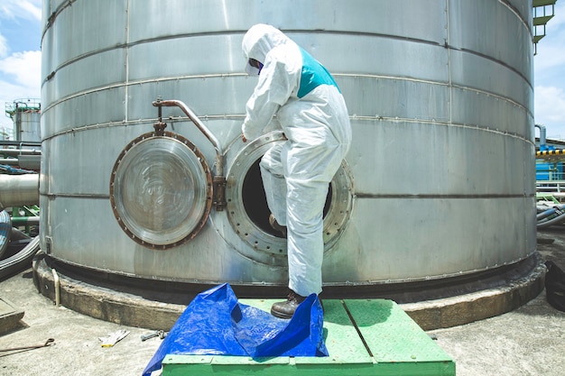 Male protective suit worker into manhole fuel stainless tank chemical protective area confined space dangerous