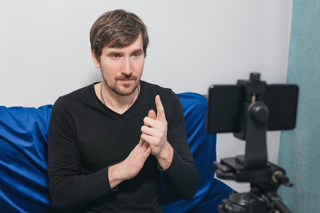 A male psychologist looking at the camera is recording a video lesson at home