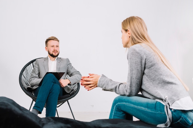 Photo male psychologist talking with his young female patient at therapy session