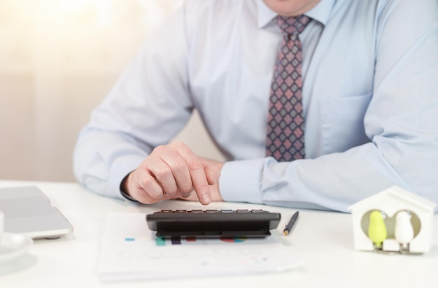 A male realtor counts the profitability of the transaction on a calculator