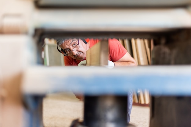 Foto uomo in maglietta rossa che lavora con una pialla in legno