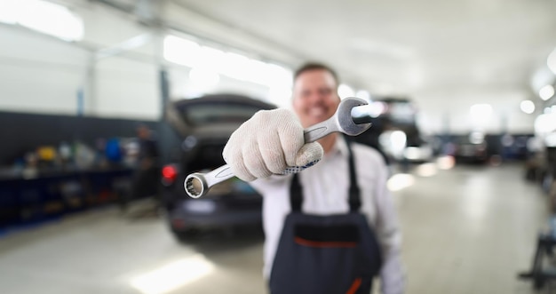 写真 自動車ワークショップのクローズアップでレンチキーを握っている男性修理員