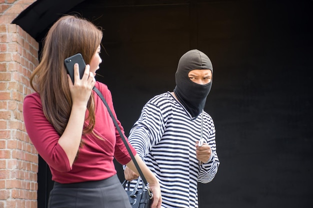 Photo male robber robbing a handbag threatening with knife to scared asian womancriminal concept