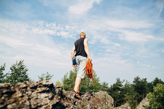 Male rock climber standing on the rock with a rope 