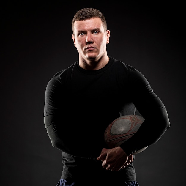 Male rugby player posing while holding ball