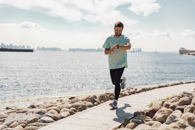 A male runner uses a fitness bracelet for a cardio trainer athlete measured in app training outside