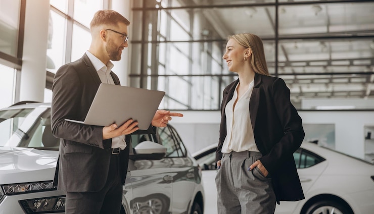 Photo a male salesman showing something on a laptop to a female client buying a car