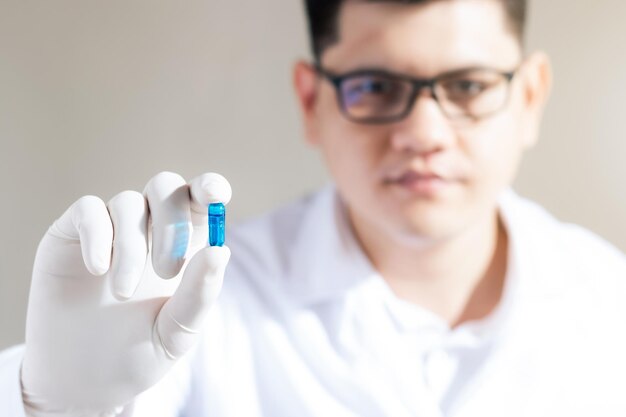 Photo male scientist hand holding a blue pill capsule in a pharmaceutical research laboratory inventing and researching drugs for serious human diseases