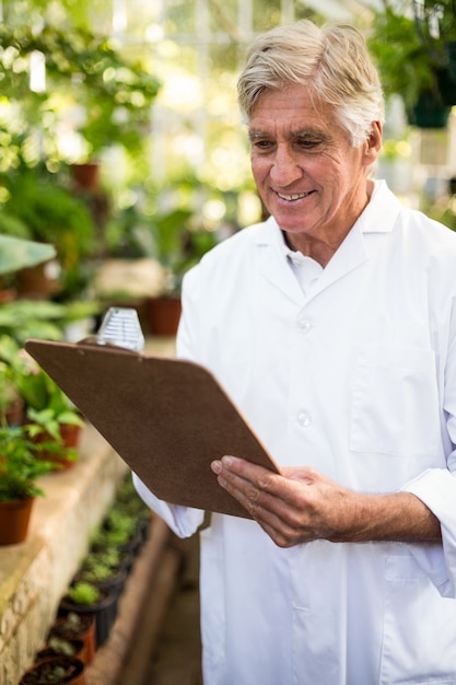 Male scientist smiling while writing on clipboard