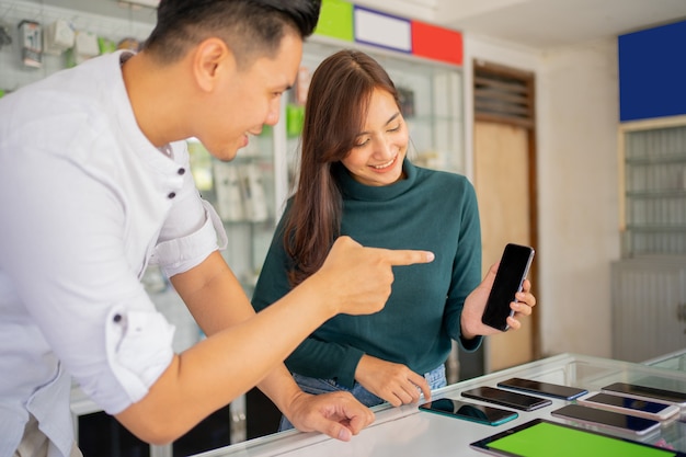 Male shop assistant guiding a female customer using a new mobile phone