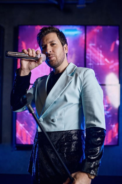 Photo male singer holding microphone standing and performing on stage