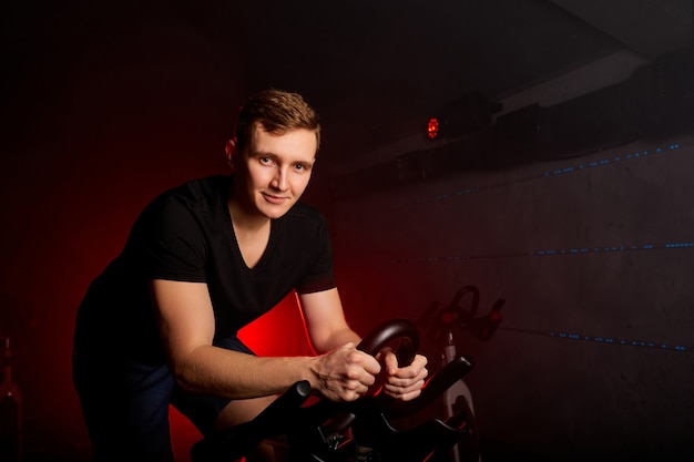 Male sitting on bike in gym posing at camera, workout ride a bike in gym, with the intention of healthcare