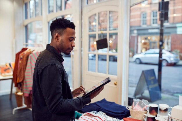 남성 소기업 소유자는 디지털 태블릿을 사용하여 상점에서 재고를 확인합니다.