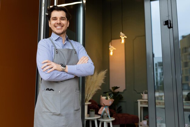 Male small business owner greets customers and customers at the door of his establishment