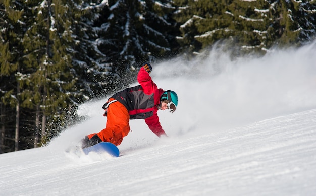 Snowboarder maschio che guida sul pendio nevoso