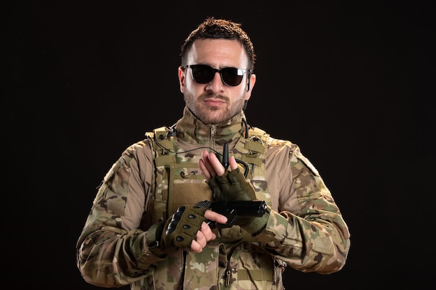 Male soldier in camouflage with gun on black wall