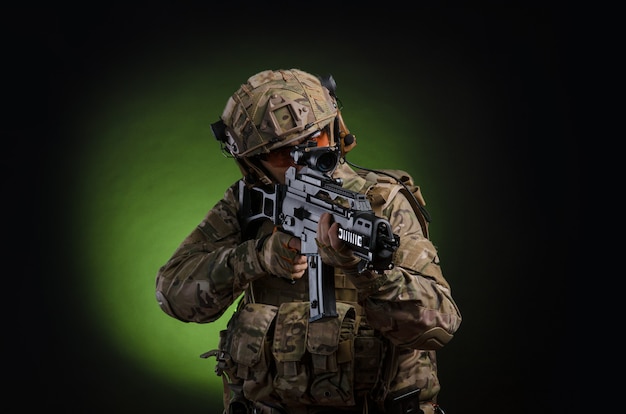 A male soldier in military clothes with a weapon on a dark background