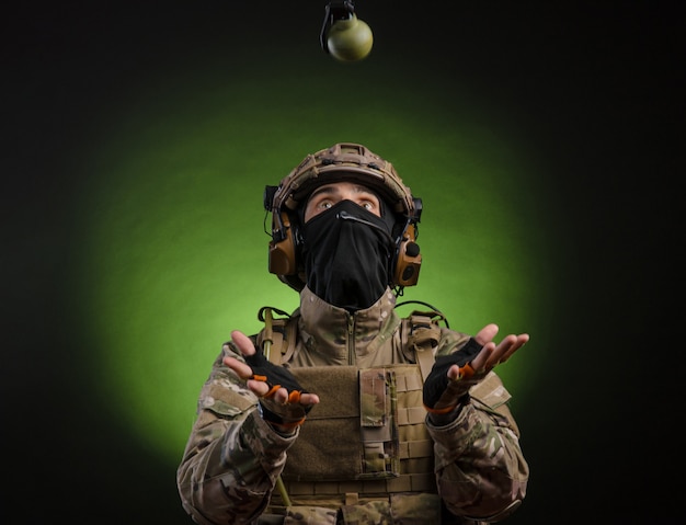 Male soldier in military dress with weapon on dark background isolated on black filmed on wide angle