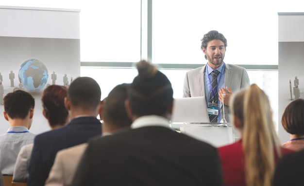 Foto un oratore maschio con un laptop parla in un seminario aziendale