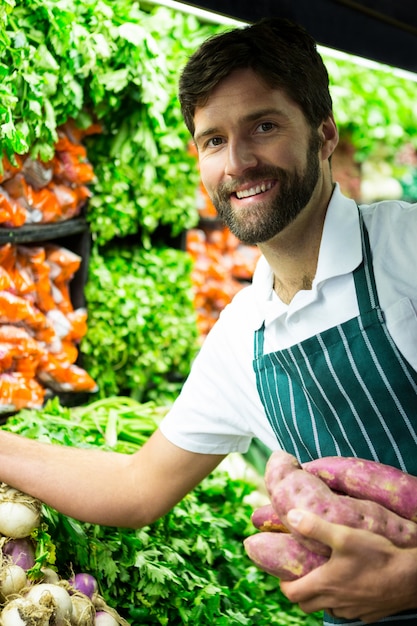 Male staff arranging vegetables in organic section
