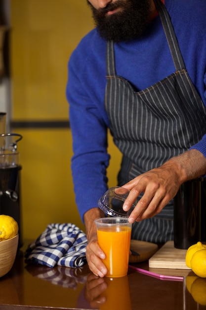 Foto personale maschile che chiude il coperchio del bicchiere di succo al bancone