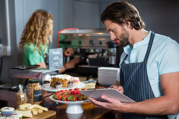 Male staff maintaining a record on clipboard at counter