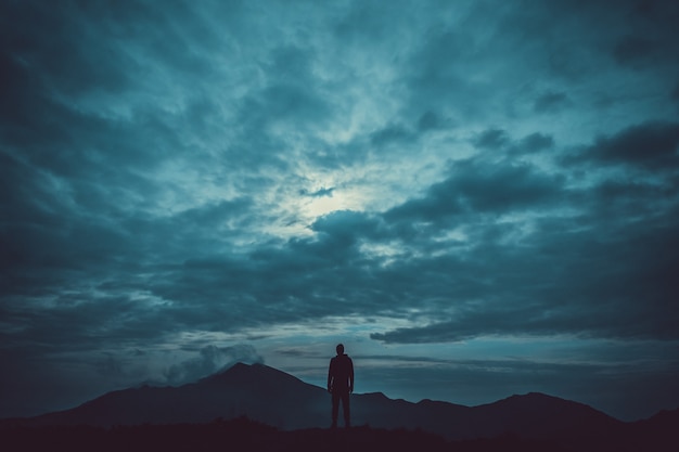 The male standing on the mountain against the cloud background