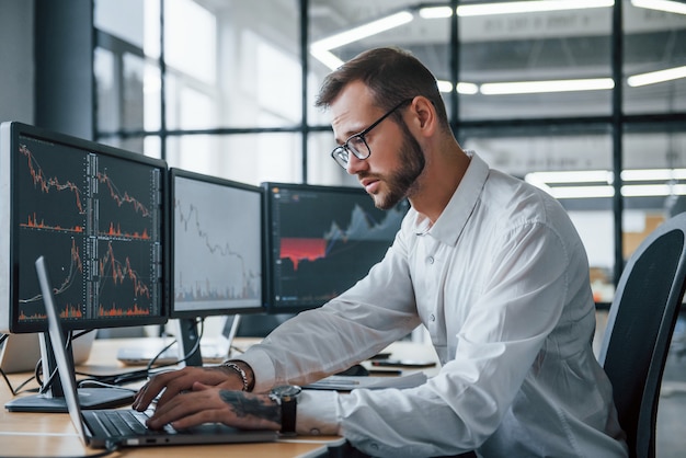 Male stockbroker in formal clothes works in the office with financial market.