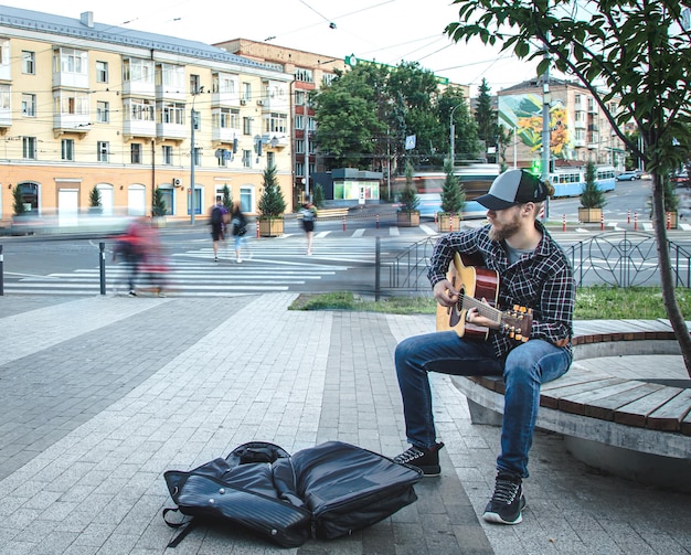 Il musicista di strada maschio suona la chitarra acustica