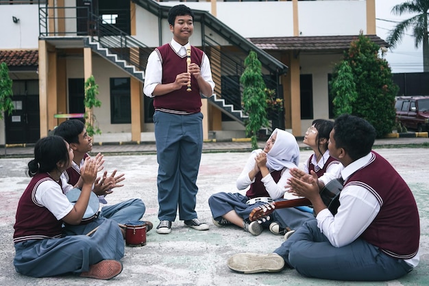 male student getting applause from his friends after playing flute music instrument at school