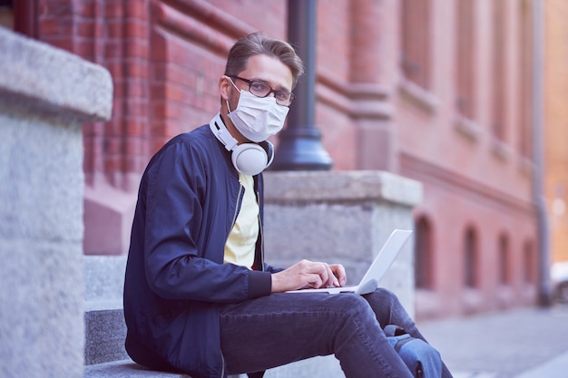 Male student hanging out in the campus wearing protective mask due to coronavirus pandemic